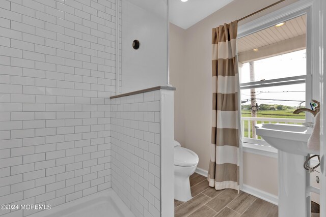 bathroom featuring toilet, a tile shower, and hardwood / wood-style flooring