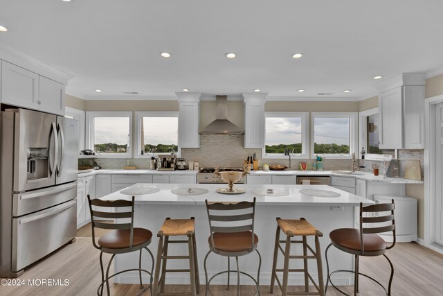 kitchen featuring backsplash, wall chimney exhaust hood, stainless steel refrigerator with ice dispenser, and plenty of natural light