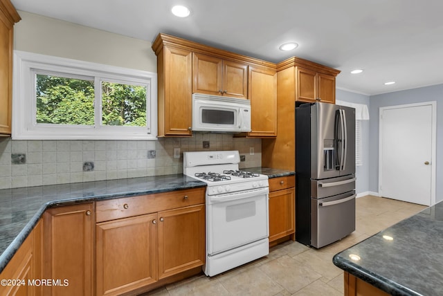 kitchen featuring white appliances, backsplash, light tile patterned floors, and dark stone counters