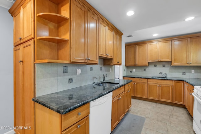 kitchen with sink, white appliances, tasteful backsplash, and dark stone countertops