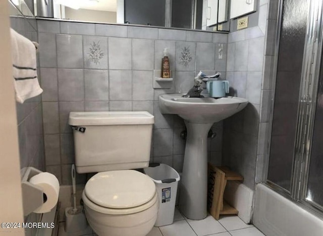 bathroom featuring tile patterned flooring, combined bath / shower with glass door, and tile walls