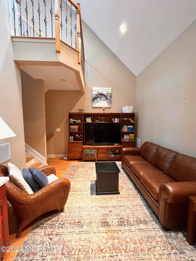 living room with high vaulted ceiling and hardwood / wood-style flooring