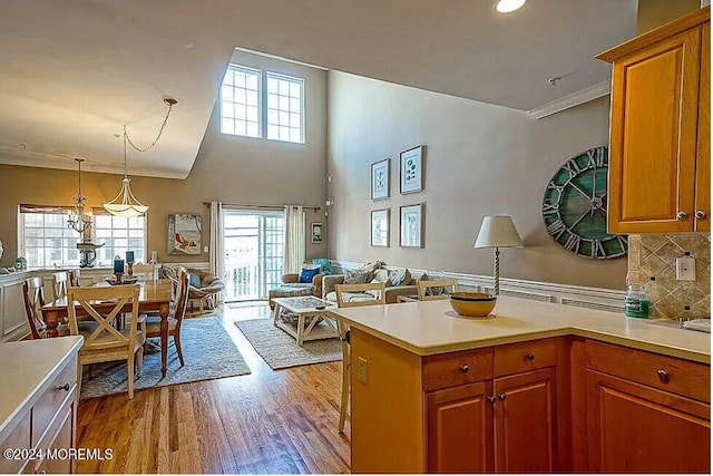 kitchen with light hardwood / wood-style floors, pendant lighting, backsplash, and a high ceiling