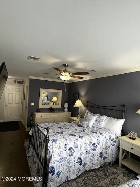 bedroom with dark hardwood / wood-style flooring, ceiling fan, and crown molding