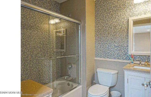 full bathroom featuring enclosed tub / shower combo, tile walls, decorative backsplash, toilet, and vanity