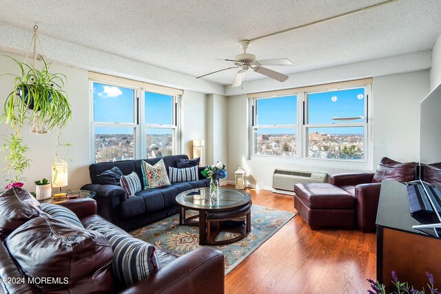 living room featuring ceiling fan, hardwood / wood-style flooring, and a textured ceiling