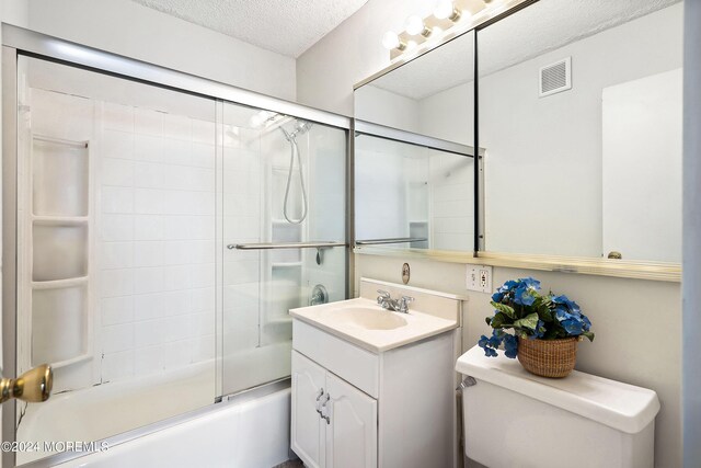 full bathroom featuring enclosed tub / shower combo, a textured ceiling, vanity, and toilet