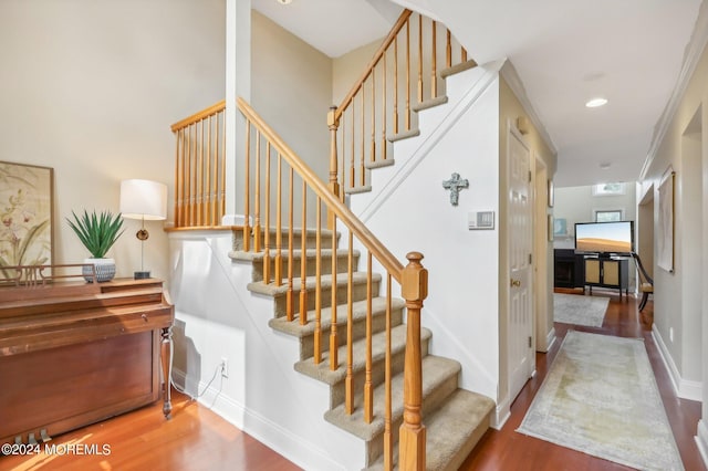 staircase featuring wood-type flooring and ornamental molding