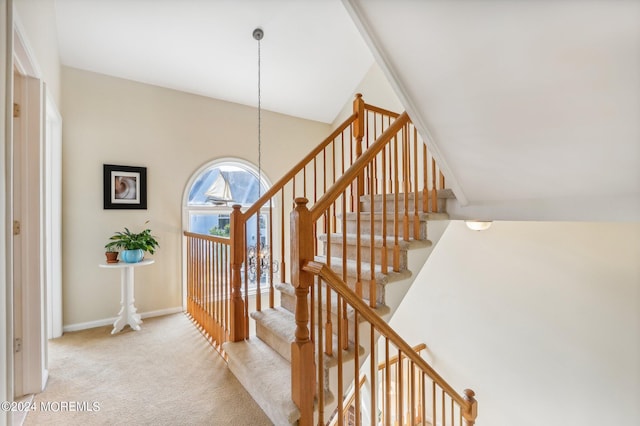 stairs with carpet, vaulted ceiling, and an inviting chandelier