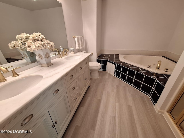 bathroom with vanity, toilet, and tiled tub