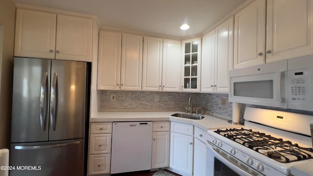 kitchen with white cabinets, backsplash, white appliances, and sink