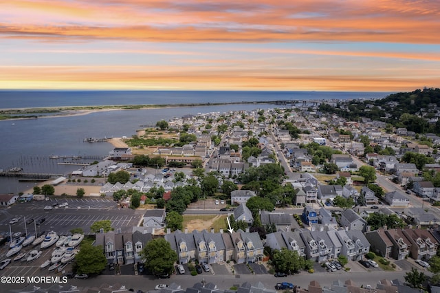 aerial view at dusk featuring a water view