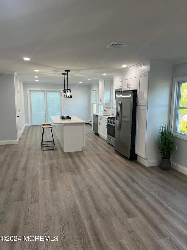 kitchen featuring a center island, white cabinets, hanging light fixtures, light hardwood / wood-style floors, and stainless steel appliances