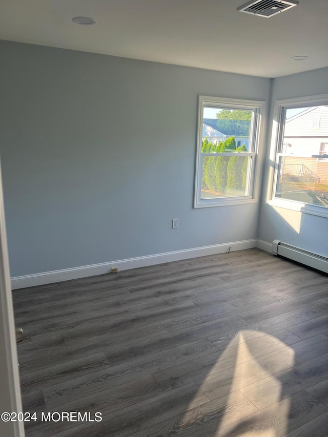 spare room featuring dark wood-type flooring and a baseboard radiator