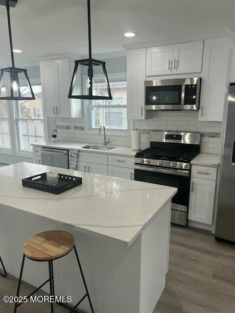 kitchen featuring appliances with stainless steel finishes, white cabinetry, and pendant lighting