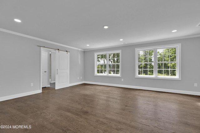 unfurnished room featuring a barn door, dark hardwood / wood-style floors, and ornamental molding