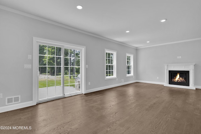 unfurnished living room with dark hardwood / wood-style flooring, crown molding, and a wealth of natural light