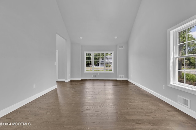 unfurnished living room with high vaulted ceiling, a wealth of natural light, and dark wood-type flooring