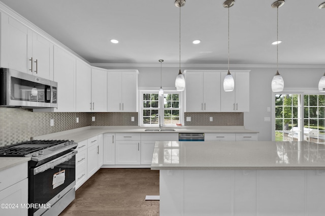 kitchen featuring sink, white cabinetry, hanging light fixtures, and appliances with stainless steel finishes