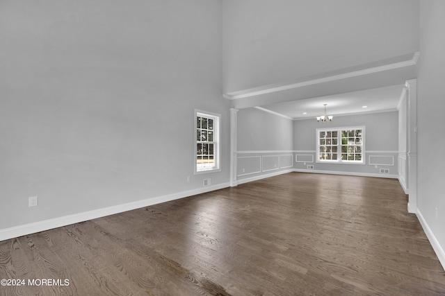 unfurnished room featuring wood-type flooring, ornamental molding, and an inviting chandelier