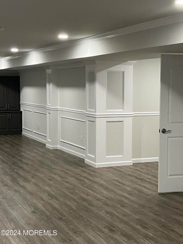 basement with dark hardwood / wood-style flooring and crown molding