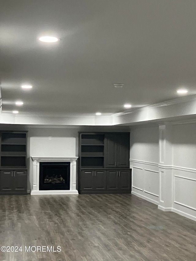 unfurnished living room with dark wood-type flooring and ornamental molding