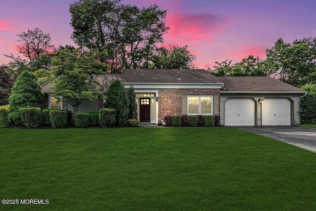 ranch-style house featuring an attached garage, a lawn, and driveway
