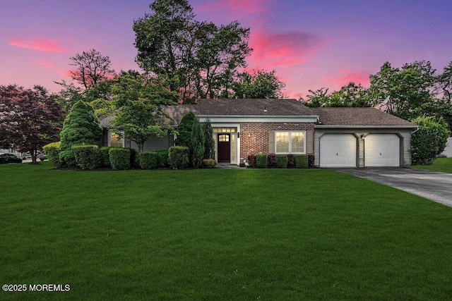 ranch-style home featuring a garage, a lawn, and driveway