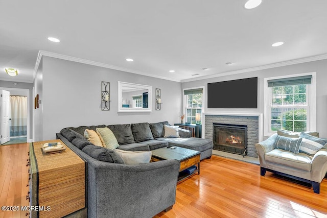 living area featuring ornamental molding, light wood-type flooring, recessed lighting, and a stone fireplace