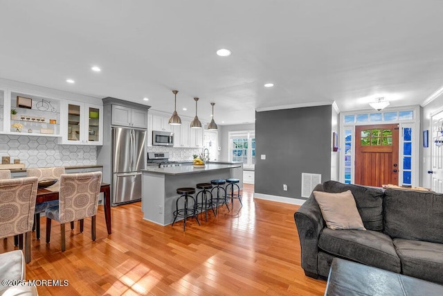 living room featuring crown molding, light wood-style flooring, recessed lighting, and baseboards