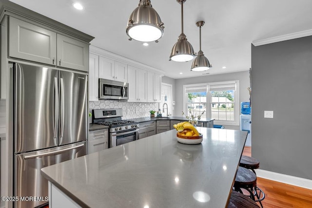 kitchen with stainless steel appliances, decorative backsplash, wood finished floors, a breakfast bar area, and dark countertops
