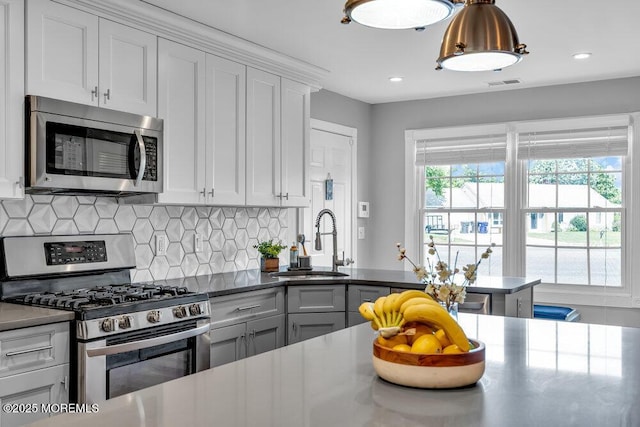 kitchen with appliances with stainless steel finishes, a sink, backsplash, white cabinetry, and recessed lighting