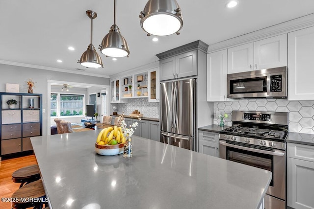 kitchen featuring stainless steel appliances, dark countertops, glass insert cabinets, a kitchen breakfast bar, and crown molding