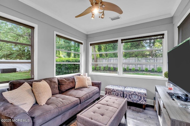 sunroom / solarium featuring healthy amount of natural light, wood finished floors, ornamental molding, and baseboards