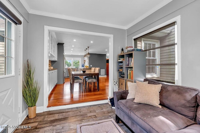 living room with wood finished floors, ornamental molding, recessed lighting, and baseboards