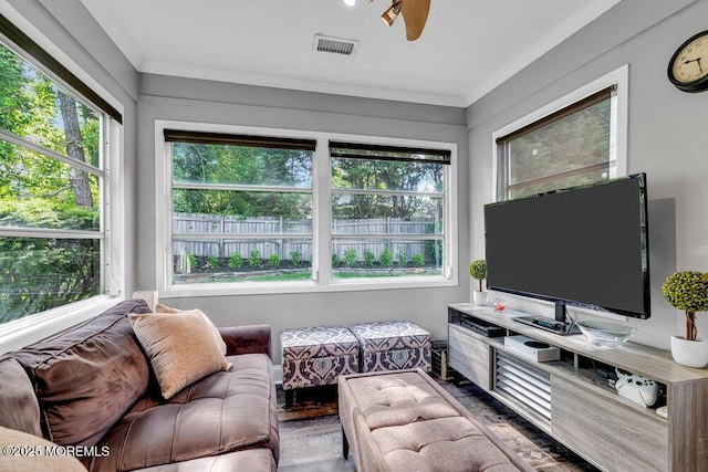 living area with plenty of natural light, wood finished floors, crown molding, and ceiling fan