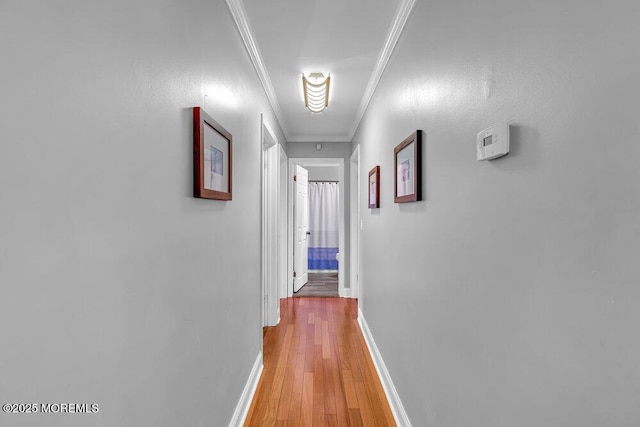 corridor with baseboards, light wood-type flooring, attic access, and crown molding