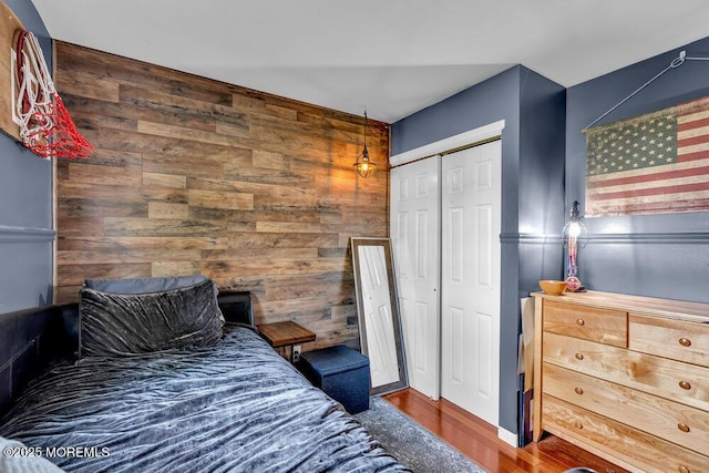 bedroom featuring wooden walls, wood finished floors, and a closet