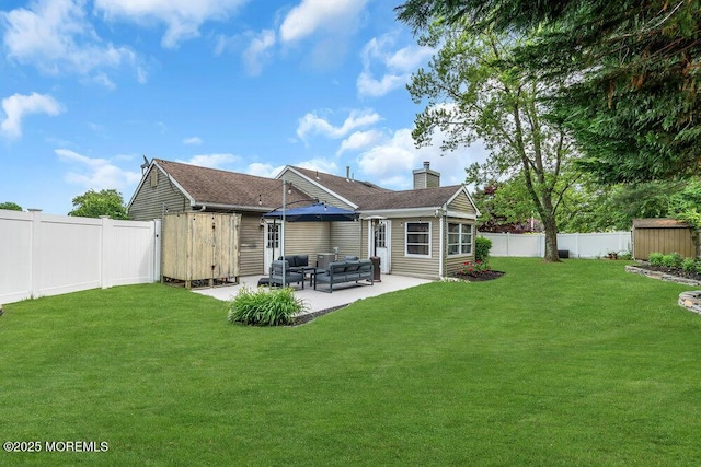 back of property featuring a storage shed, a patio area, a chimney, an outbuilding, and an outdoor living space