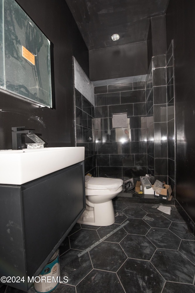 bathroom with vanity, toilet, and tile walls