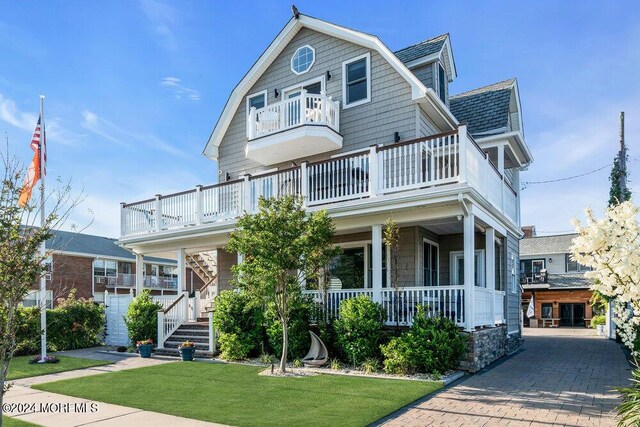 view of front facade with a garage, a front lawn, covered porch, and a balcony