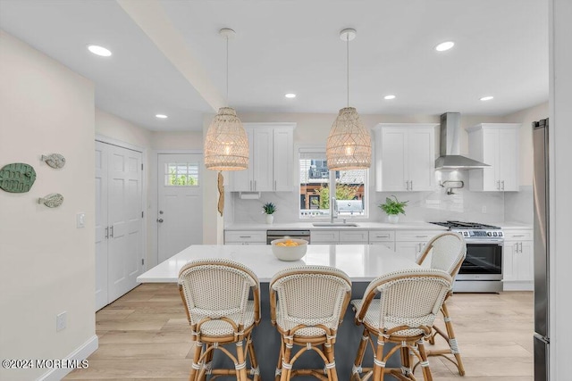 kitchen with white cabinetry, wall chimney range hood, sink, and appliances with stainless steel finishes