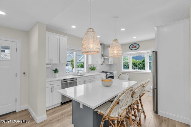 kitchen featuring stainless steel appliances, a kitchen island, pendant lighting, and white cabinets