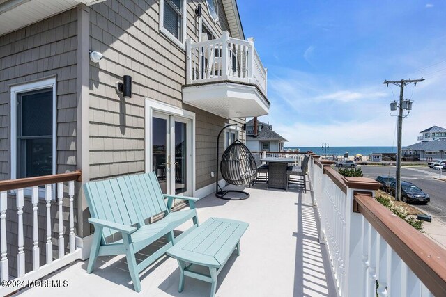 balcony featuring french doors and a water view