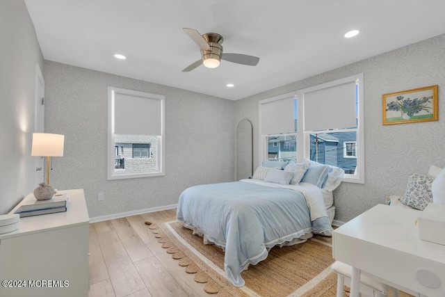 bedroom with multiple windows, light hardwood / wood-style floors, and ceiling fan