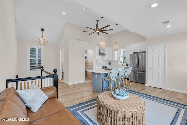 living room featuring ceiling fan, high vaulted ceiling, sink, and light hardwood / wood-style flooring