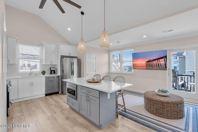 kitchen with sink, white cabinetry, decorative light fixtures, a kitchen island, and stainless steel appliances