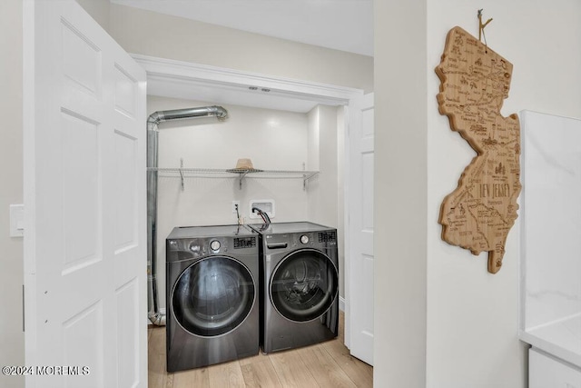 clothes washing area with separate washer and dryer and light hardwood / wood-style flooring