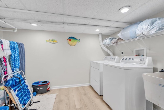 laundry room with separate washer and dryer, sink, and light hardwood / wood-style flooring