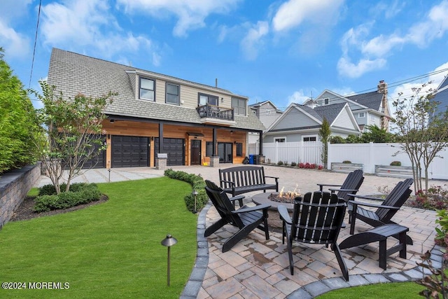 rear view of house featuring a fire pit, a lawn, a patio area, a garage, and a balcony